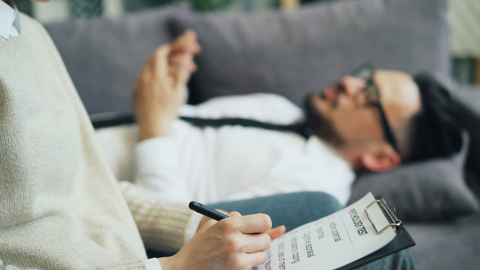 a-person-laying-on-a-couch-writing-on-a-piece-of-paper.jpg a person laying on a couch writing on a piece of paper